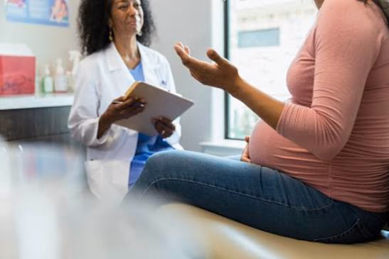 Une femme enceinte échange avec sa médecin en consultation.